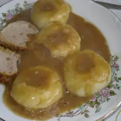 Kluseczki śląskie z mięsem i sosem na talerzu z kwiatowym wzorem.