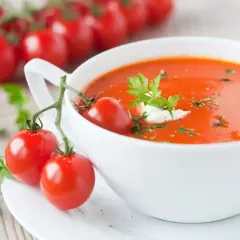 Miseczka zupy pomidorowej z pomidorkami koktajlowymi i natką pietruszki.