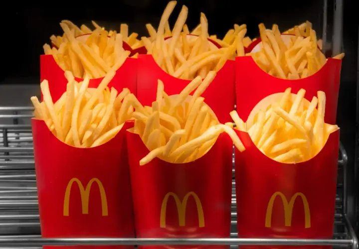 Kilka czerwonych opakowań frytek z logo McDonald's.
