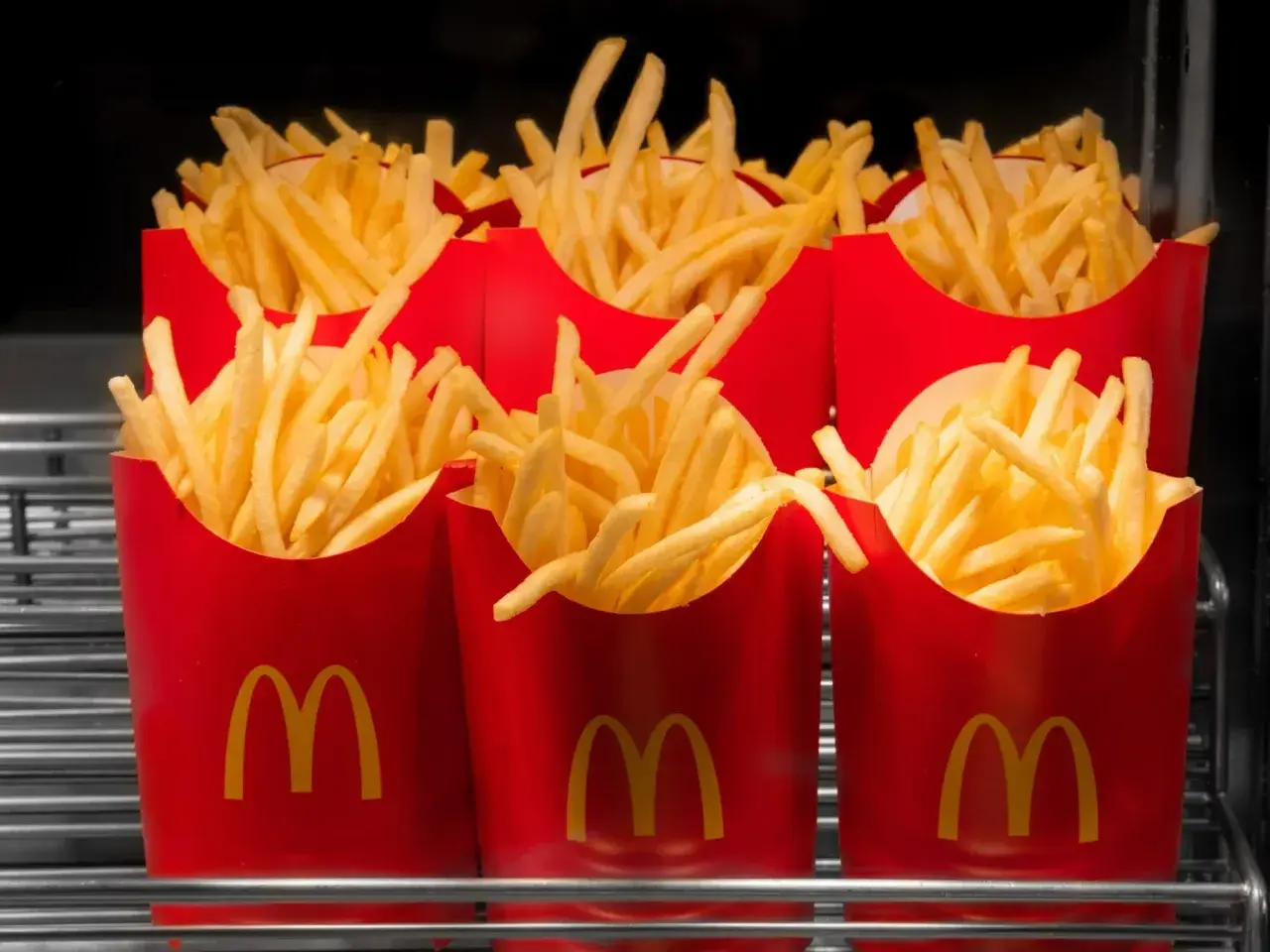 Kilka czerwonych opakowań frytek z logo McDonald's.
